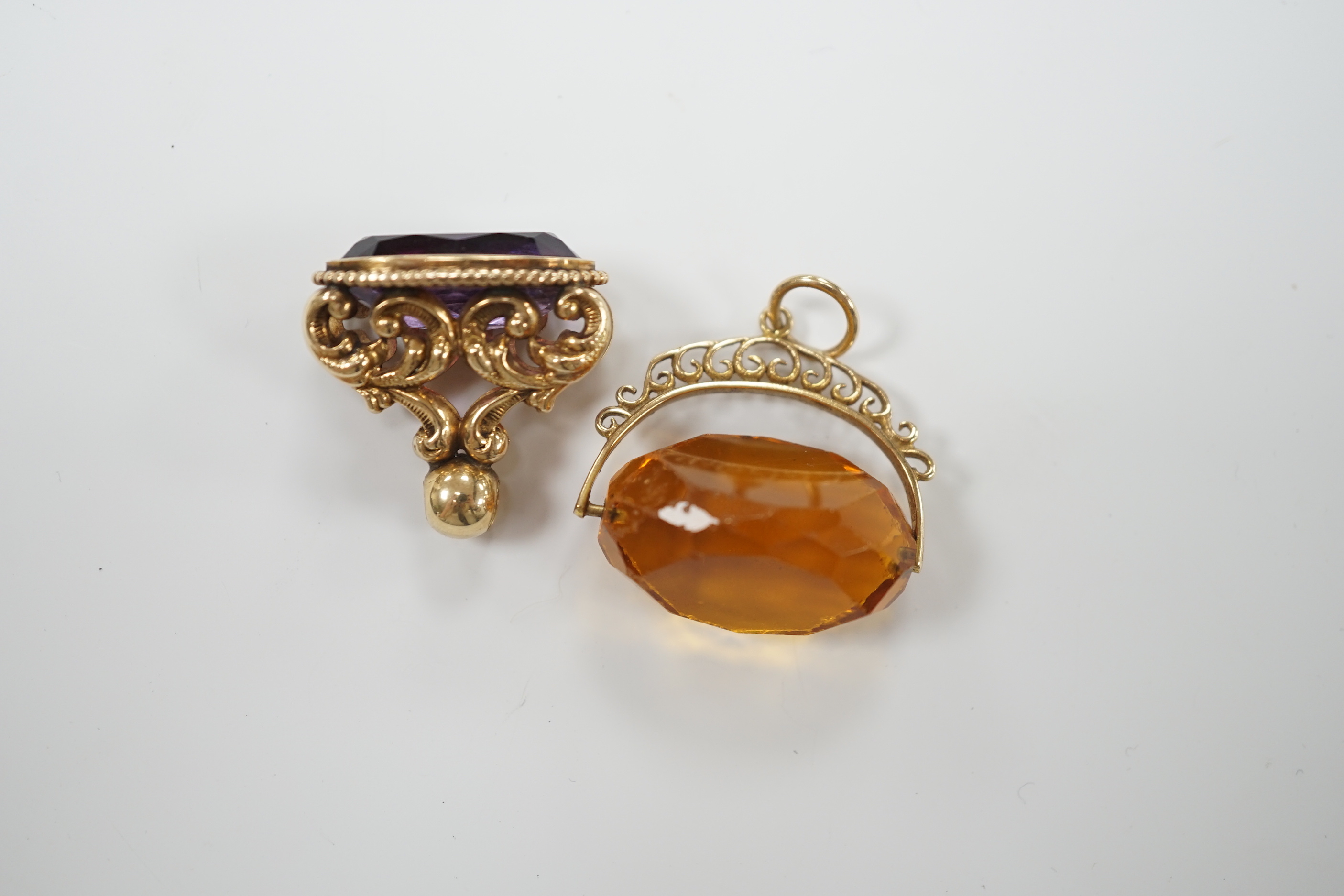 A yellow metal and amethyst set spinning fob, 22mm and one other 9ct gold and gem set fob, gross weight 15.5 grams.